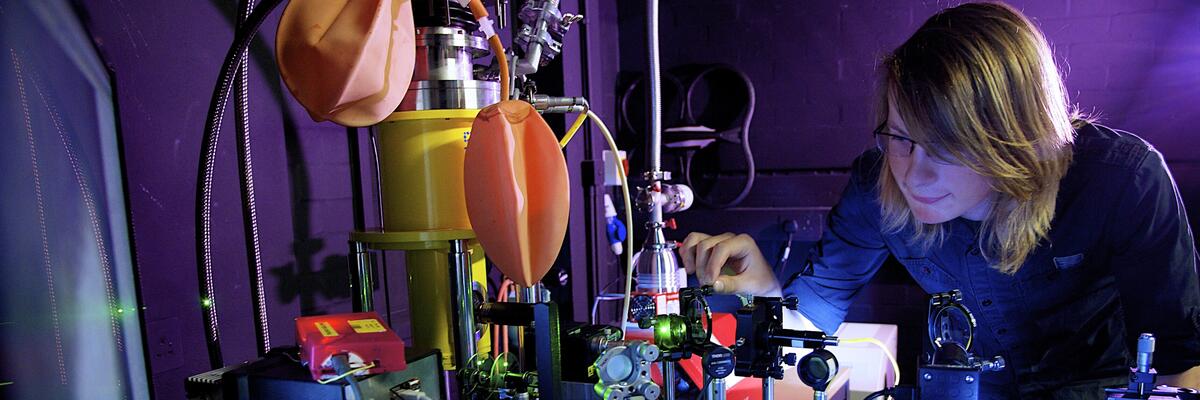 An academic examining some equipment within Physics