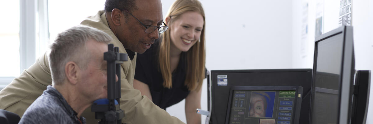 An academic and a student conducting an eye-tracking test on an older man
