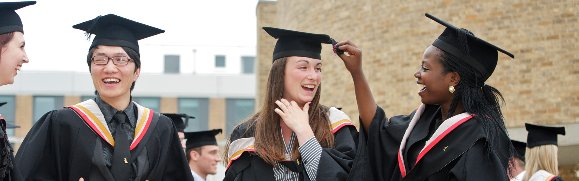 Graduating students share a joke whilst dressed in caps and gowns