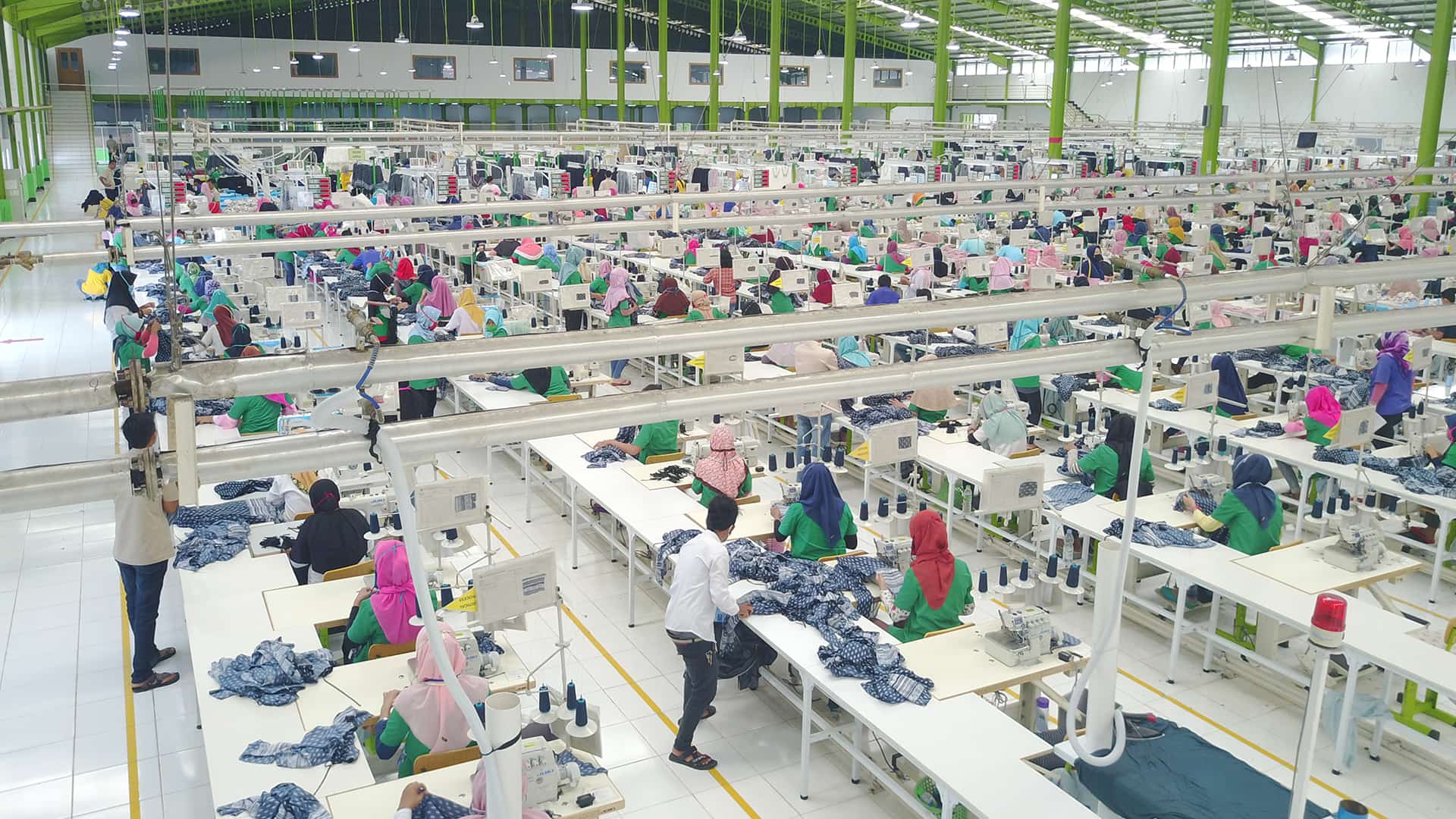 A large warehouse filled with people working at sewing machines