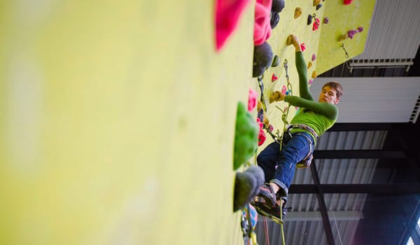 A person high up on a climbing wall in the Sports Centre